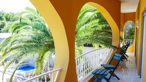 Un pasillo con ventanales arqueados, bancos azules y una zona de piscina visible a través de las ventanas.