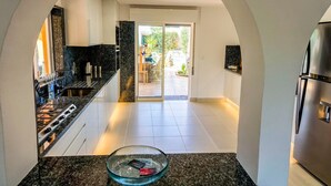 Una cocina moderna con encimera de granito, un tazón de vidrio y un refrigerador de acero inoxidable.