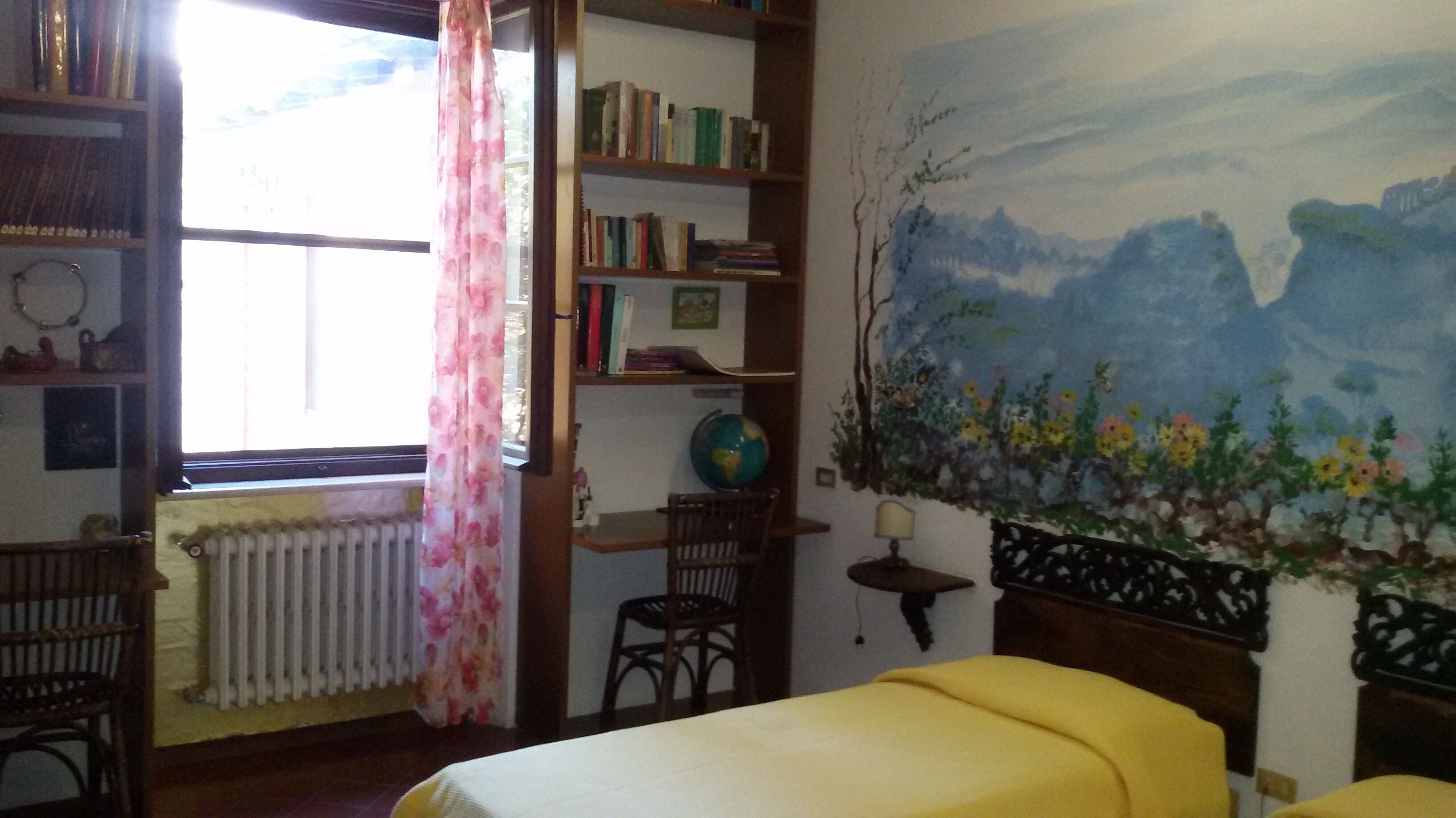 Una habitación con una cama, una estantería, un globo terráqueo y un cuadro.