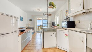 Een moderne keuken met witte kasten, een ingebouwde vaatwasser, een koffieapparaat en uitzicht op het buiten.