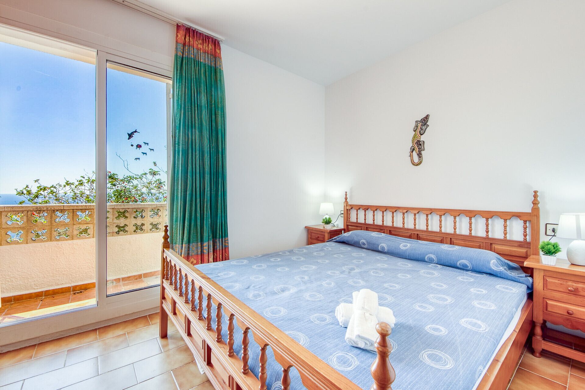 Une chambre à coucher comprenant un lit, une table de chevet, une lampe, un luminaire fixé au mur et un balcon avec vue.