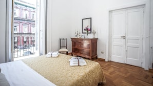 A bedroom with a large bed, a wooden dresser, a chair, and a wardrobe. - Neapolitan house, unique history and view (Napoli)