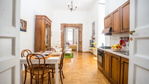 A kitchen with wooden cabinets, a dining table with chairs, and a view into the living room. - Neapolitan house, unique history and view (Napoli)