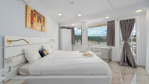 A modern bedroom with a large bed, a desk, and a view of the city. - Urban Loft with balcony across the Acropolis! (Athina)