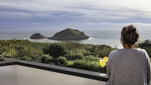 A balcony with a view of the sea and two small islands.