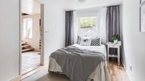A bedroom with a bed, a nightstand, a window with curtains, and a door leading to another room. - Partille Homestay. 4 rooms with kitchen. (Partille)