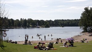 A lakeside beach with people swimming and relaxing on the shore. - Partille Homestay. 4 rooms with kitchen. (Partille)