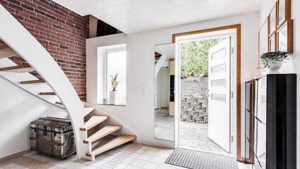 A modern interior with a staircase, a door leading outside, and a small plant on a cabinet. - Partille Homestay. 4 rooms with kitchen. (Partille)