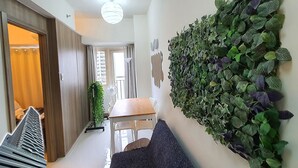 Un intérieur moderne avec une armoire en bois, une table à manger avec des chaises, une plante fixée au mur et une vue sur le paysage urbain par la fenêtre.