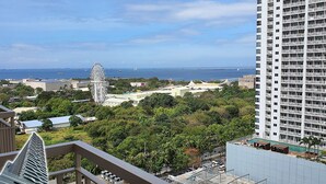 Un immeuble de grande hauteur offrant une vue sur une zone côtière, notamment une grande roue et une piscine.