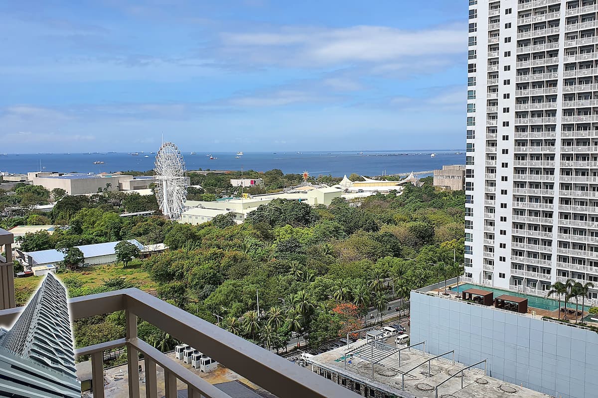 Um edifício alto com vista para a área costeira, incluindo uma roda-gigante e uma piscina.