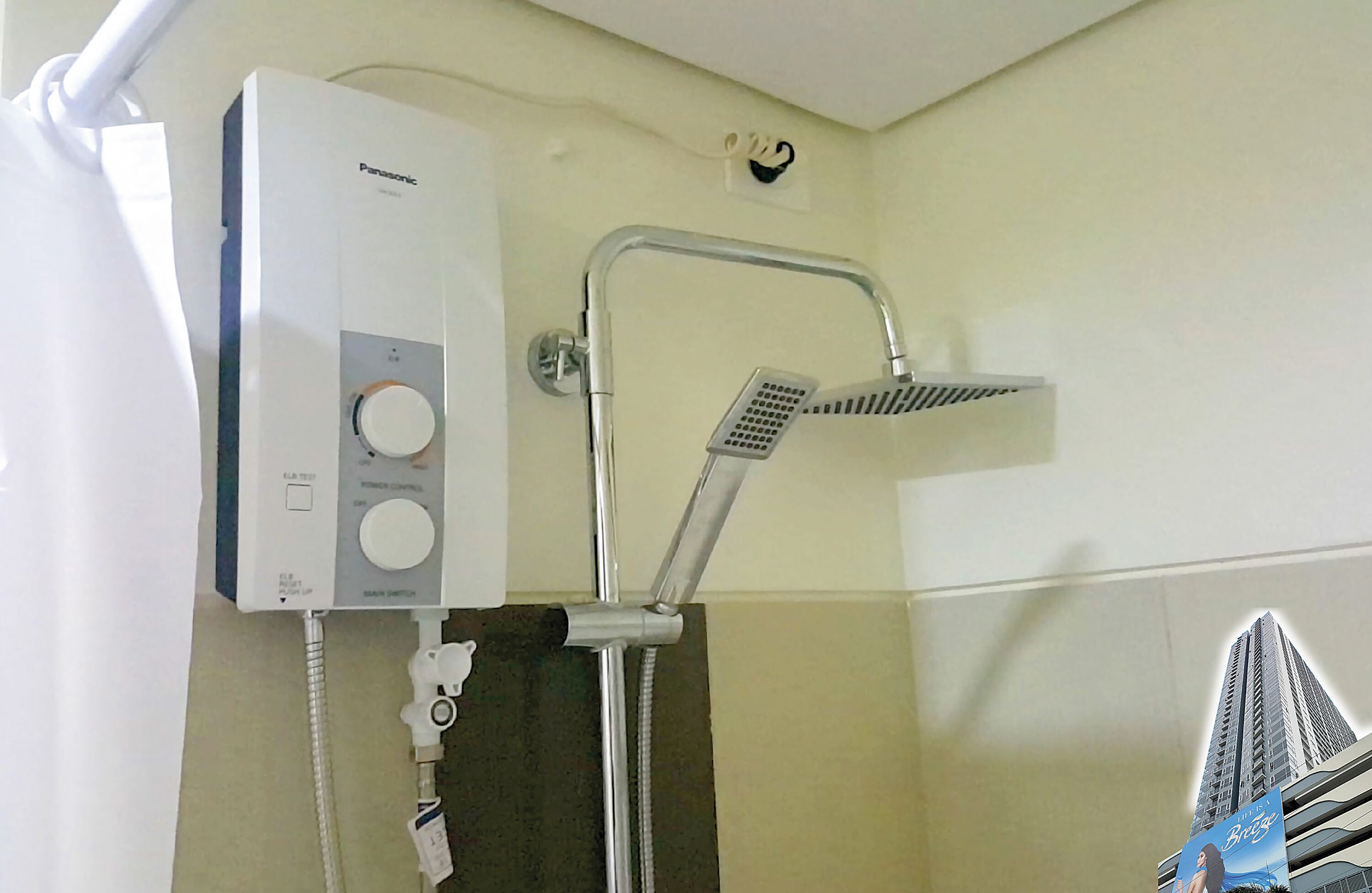 A bathroom with a Panasonic water heater, a shower with a handheld showerhead, and a towel rack.