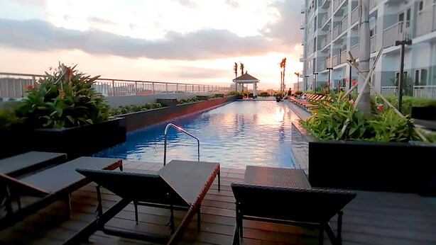 Une piscine sur le toit, dotée de chaises longues, d’un belvédère et offrant une vue sur le coucher de soleil.