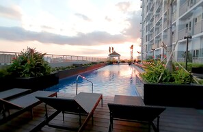 A rooftop pool with lounge chairs, a gazebo, and a view of the sunset. - Home Sweet Home at Manila Bay (Pasay)