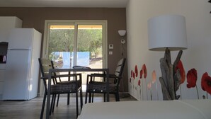 Ein Zimmer mit Esstisch, Stühlen, einem Kühlschrank, einer Lampe und einer Wandmalerei mit Blumen.