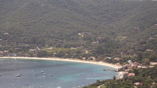 Eine Küstenstadt mit Strand, Booten und einem Bergpanorama.