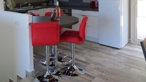 Eine moderne Küche mit weißen Schränken, einem weißen Kühlschrank und roten Stühlen.