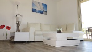 Ein modernes Wohnzimmer mit einem weißen Sofa, einem Beistelltisch mit Lampe und einem Gemälde eines Segelboots.