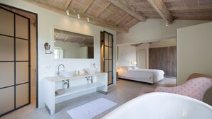 Un baño moderno con una bañera independiente, un tocador doble y un espejo grande.