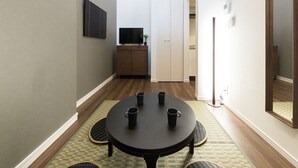 A hallway with a round table, four black mugs, and a television on a cabinet. - Trip Pod Takasago A (Fukuoka)