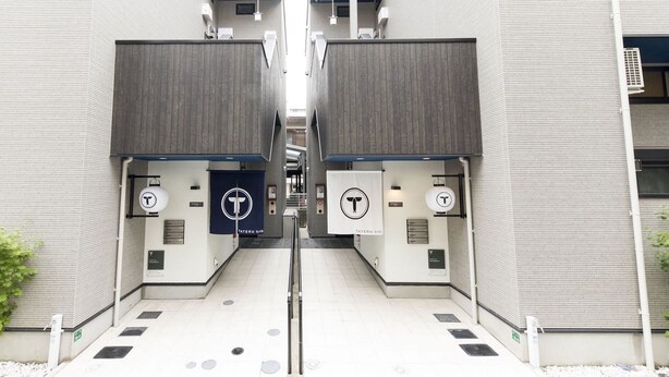 A symmetrical building facade with two entrances, each marked by a 'T' logo and a sign reading 'TATERU onb'. - Trip Pod Takasago A (Fukuoka)