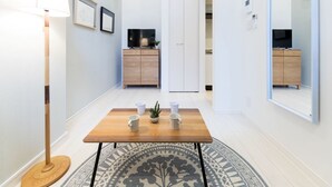 A hallway with a wooden table, a floor lamp, and a patterned rug. - Trip Pod Takasago A (Fukuoka)
