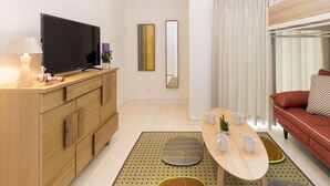 A modern living room with a TV, sofa, and a dining table with cups and a plant. - Trip Pod Takasago A (Fukuoka)