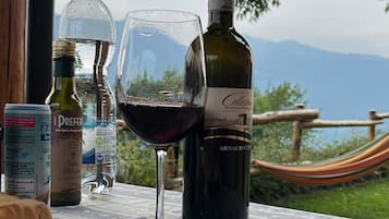 A table with a bottle of wine, a glass, and a plate of food, set against a scenic outdoor backdrop.