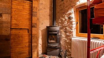 Una habitación rústica de madera con pared de piedra, puerta de madera, chimenea y ventana.