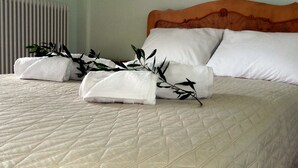A neatly made bed with white linens, a quilted duvet, and a decorative branch. - villa anthousa  with excellent view (ANTHUSA)