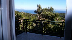 A balcony with a view of a coastal landscape, including trees and distant mountains. - villa anthousa  with excellent view (ANTHUSA)