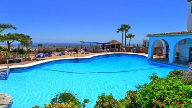 A swimming pool with lounge chairs and a view of the ocean.