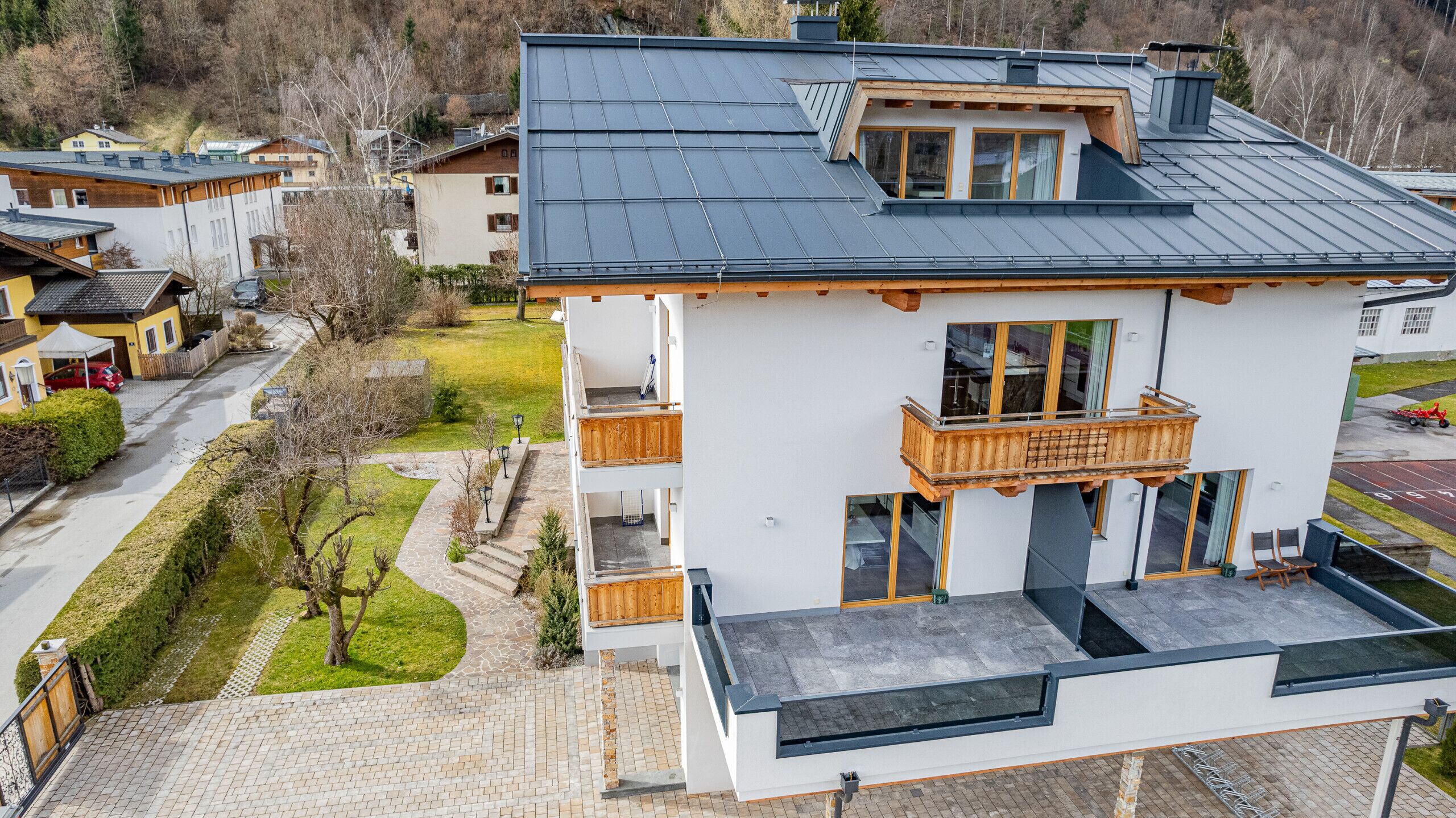 Un bâtiment moderne à deux étages, doté d’un balcon, d’un chemin en pierre menant à l’entrée et offrant une vue sur le quartier environnant.