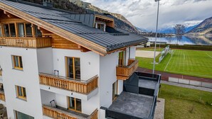 En byggnad med flera våningar, träbalkonger, en tennisbana och utsikt över en sjö.