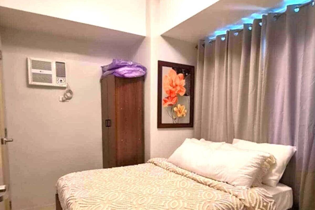 Une chambre à coucher avec un lit, une porte, une fenêtre et un climatiseur fixé au mur.
