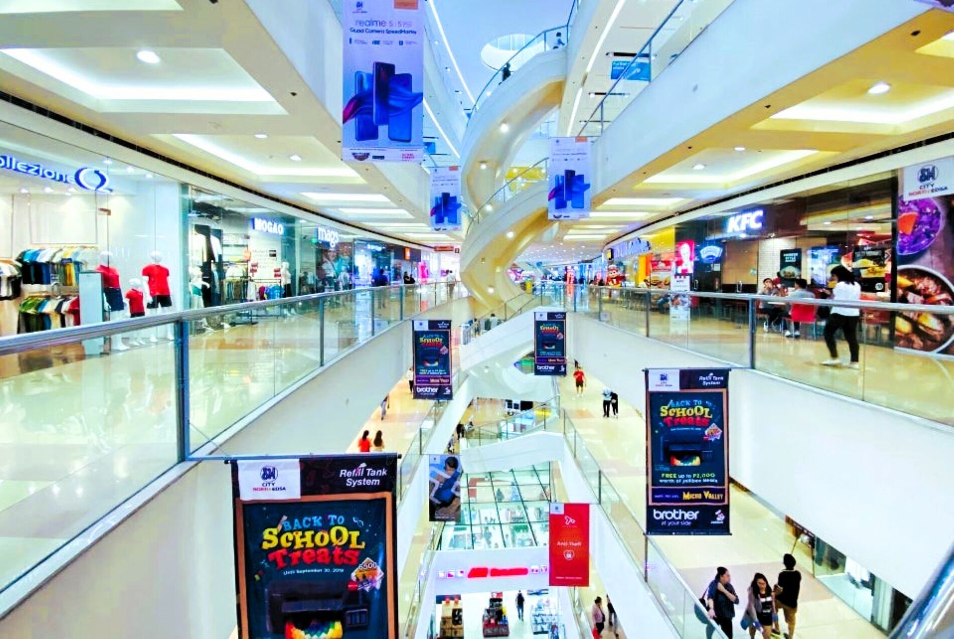 A multi-level shopping mall with various stores and promotional banners.