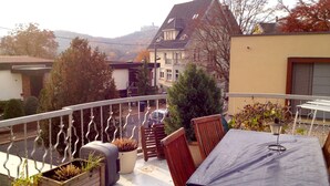 A balcony with a table and chairs, potted plants, and a view of buildings and trees. - Duplex apartment in Südstadtvilla (Eisenach)