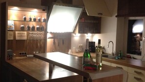 A modern kitchen with a bar area, wooden cabinets, and a countertop with a bottle of wine. - Duplex apartment in Südstadtvilla (Eisenach)