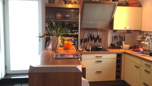 A kitchen with a wooden countertop, a potted plant, a kettle, and various kitchen utensils. - Duplex apartment in Südstadtvilla (Eisenach)