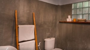 A bathroom with a wooden ladder, a toilet, a sink, and a window with a shelf above it. - The Orientation Lodge (Siem Reap)