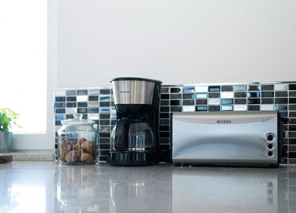 A kitchen with a coffee maker, a jar of cookies, and a toaster.