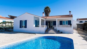 A modern house with a swimming pool, a balcony, and a clear blue sky.
