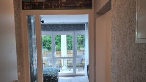 Un pasillo con vistas a un mural de la ciudad, una puerta de cristal que da a un balcón con mobiliario exterior y una pared con diseño.