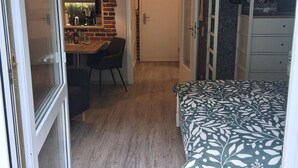 Un dormitorio con cama, escritorio y silla, armario y puerta que da a otra habitación.