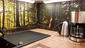 Una cocina con encimera negra, un hervidor de acero inoxidable y una cafetera.