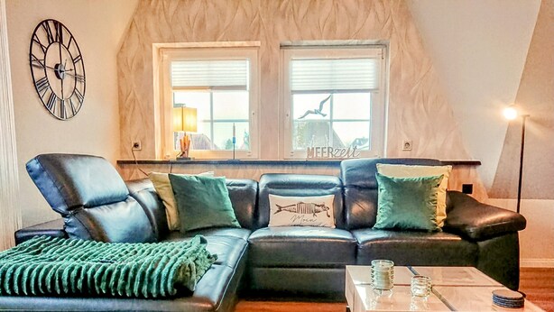 A modern living room with a sectional sofa, a coffee table, and a wall clock. - **** classified comfort vacation apartment 300 m to the beach, incl. beach chair  (Grömitz)