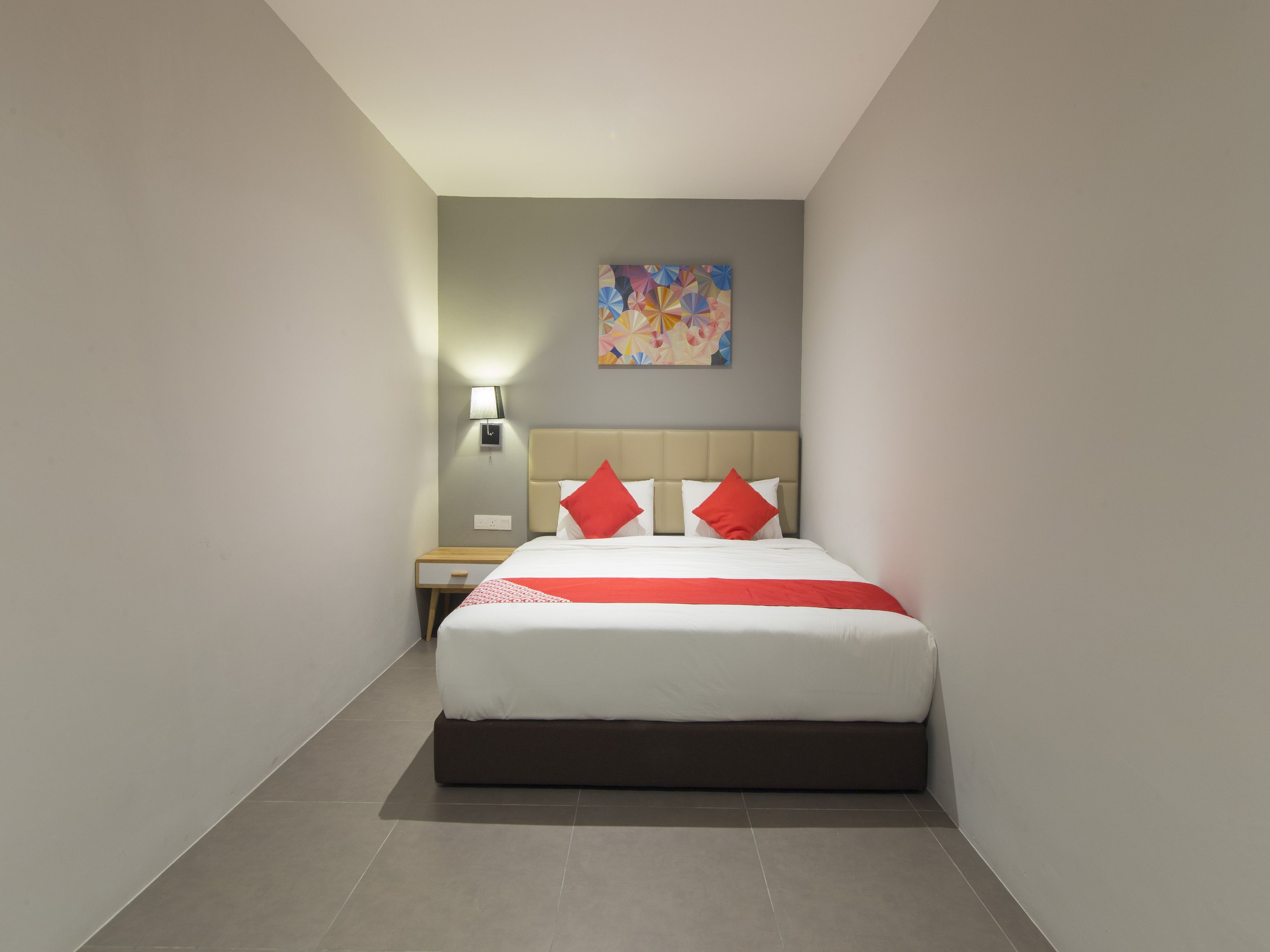 A modern hotel room with a bed, nightstand, and a painting on the wall.