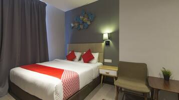 A hotel room with a bed, a nightstand, a chair, a small table, and a wall decoration.