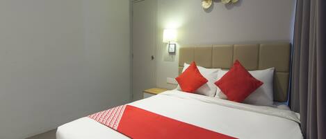 Una camera d'albergo con un letto, un comodino, una lampada a parete e un elemento decorativo a parete.