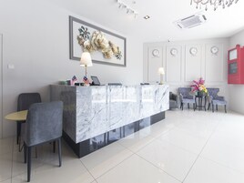 A modern reception area with a marble counter, two flags, a sofa, and a clock displaying time in four cities.